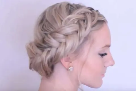 Wiesn Frisur kurze Haare: Ein geflochtener Kranz um den Kopf, der wie ein Haarband wirkt, mit einem Dutt im Nacken.