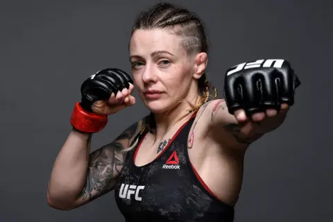 Joanne Calderwood, en MMA-fighter med flätor och tatueringar, visar upp sina boxningshandskar redo för strid.
