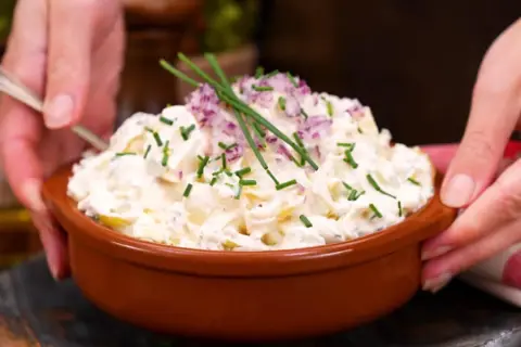 En skål med krämig potatissallad, toppad med rödlök och gräslök. Ett ljuvlig potatissallad recept som passar till allt!