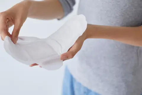 Hände halten ein Inkontinenzprodukt. Fragen Sie Ihren Arzt, wo Sie Inkontinenzmaterial auf Rezept bekommen.