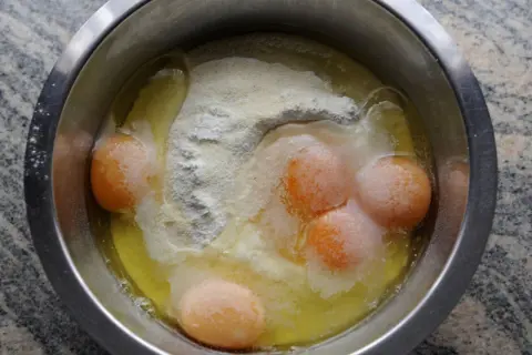 Rohe Eier und Mehl in einer Schüssel. Manche Leute essen Mehl roh, aber das ist nicht empfehlenswert.