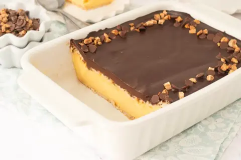 Tarta de natillas y galletas con cobertura de chocolate y trocitos de galleta y chocolate.