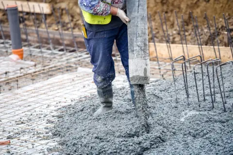 Robot wylewa beton na zewnątrz, tworząc solidną wylewkę betonową.