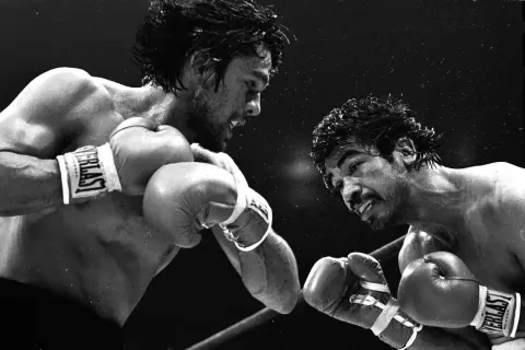 Two boxers face off. The boxer on the left, with a determined look, is Roberto Duran, from Panama. He throws a punch.