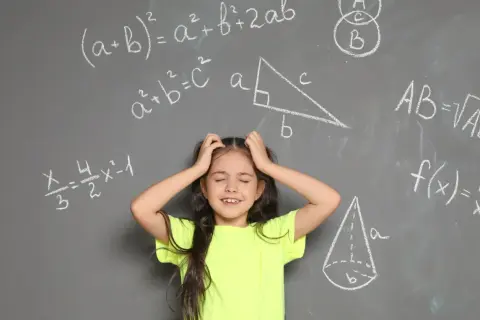 Dziewczynka z rękami wplątanymi we włosy, wyraźnie przeżywająca problemy z matematyką. Wokół niej wzory i figury geometryczne na tablicy.