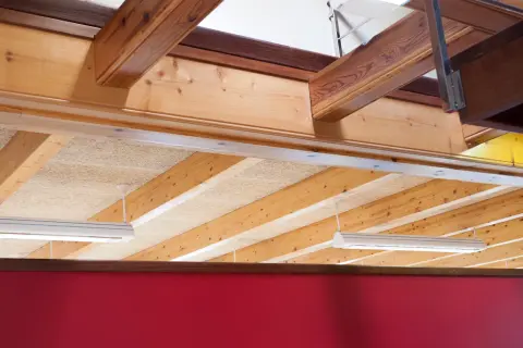 Detalle constructivo de forjado de madera con vigas expuestas y paneles aislantes.