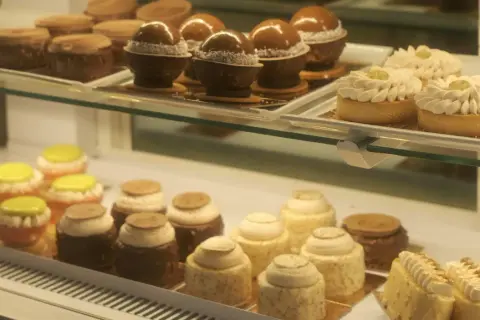 Słodkości w kawiarni cukierni Cafe Marona Gruszecki: czekoladowe kule, tartaletki z kremem i kolorowe babeczki.