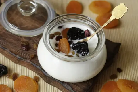 Jogurt z suszonymi owocami i złotą łyżeczką – idealne szybkie śniadanie na ciepło.