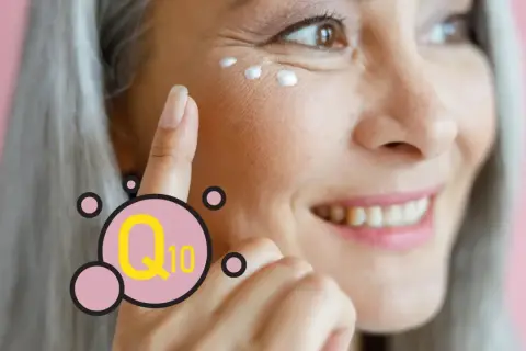 Mujer sonríe mientras se aplica crema en el contorno de ojos. El Q10 es un ingrediente clave para el cuidado de la piel.