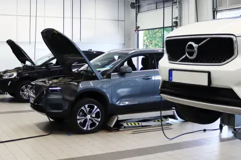 Flera Volvo-bilar, inklusive en vit XC40 och en grå elbil, på verkstad för volvo classic service. Motorhuvar öppna för inspektion.
