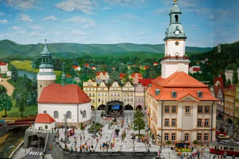 Miniaturowy rynek w Jeleniej Górze, z wieżą ratuszową, kamieniczkami i tłumem ludzi.