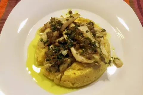Delizioso luccio alla gardesana su un letto di polenta, condito con erbe aromatiche e olio d'oliva.