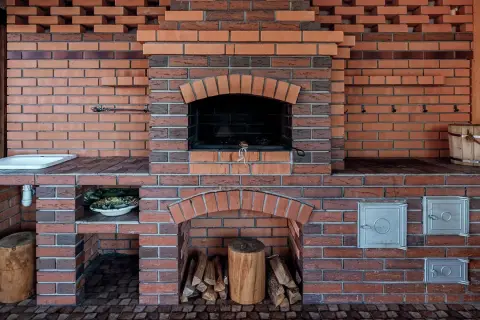 Murowany grill z cegły z paleniskiem, miejscem na drewno i umywalką.