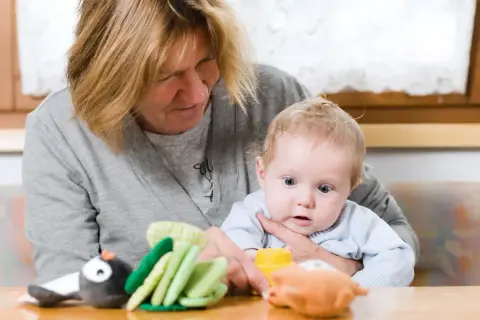 Babcia z czułością opiekuje się wnukiem, pokazując mu zabawki.