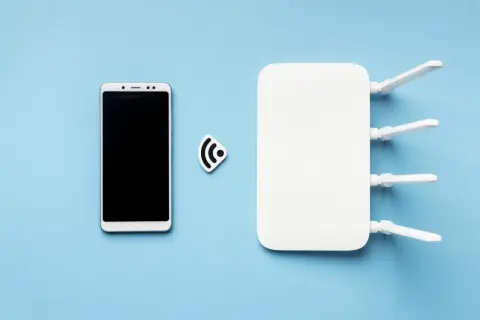 Smartfon i router Wi-Fi symbolizują, jak udostępnić internet z telefonu na laptopa.