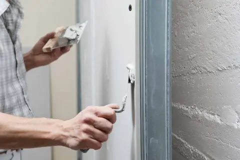 Un artisan applique un enduit de finition sur un mur avec une truelle, préparant la surface pour une peinture parfaite.