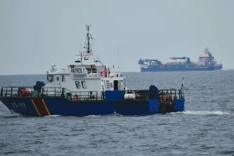 Kuter Straży Granicznej "PATROL 1" płynie po morzu. W tle widać duży statek "Van Oord".