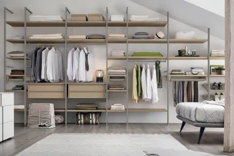 Una cabina armadio mansarda bassa, con scaffali in legno e metallo, ospita abiti ordinati e accessori.