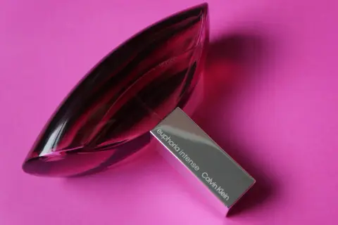 Perfumy Calvin Klein Euphoria Intense w szklanej, fioletowej butelce na różowym tle.