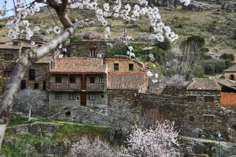 Casas de piedra con tejados rojos en un pueblo de montaña, ideal para saber como ir a la sierra de Madrid en primavera.