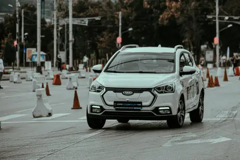 Voiture blanche lors d'un stage de sensibilisation à la sécurité routière, slalomant entre des cônes et des barrières.