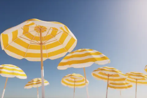Gula och vita parasoller mot en klarblå himmel, en perfekt bild av arbetsfria dagar.