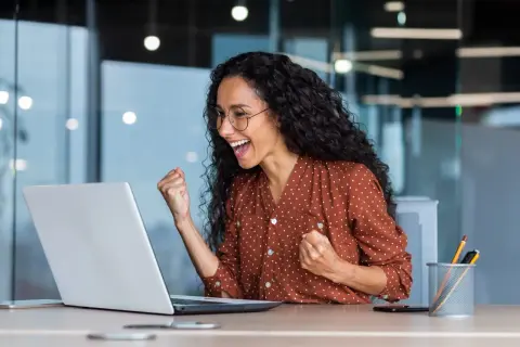 Excited woman celebrates fast Google Drive upload speed on her laptop.