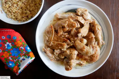 Alitas de pollo al ajillo, doradas y jugosas, servidas en un plato blanco. Acompañadas de quinoa y una servilleta colorida.