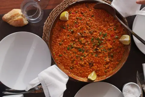 Paella mixta, un clásico que no puede faltar si te preguntas qué comer en Cabo de Gata. Servida en una paellera, con limón y pan.