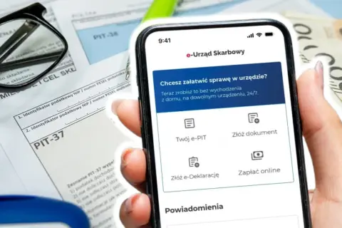 Telefon z aplikacją e-Urząd Skarbowy obok formularzy PIT i pieniędzy. Wpisz swój numer identyfikacji podatkowej, by załatwić sprawy urzędowe online.