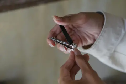 Une main utilise un coupe-ongles pour couper un ongle homme.