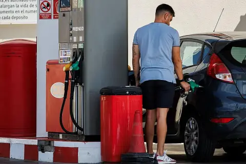 Hombre repostando su coche con gasolina 98. El surtidor muestra opciones de combustible, incluyendo la opción de alta octanaje.