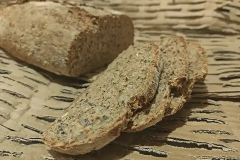 Wilgotny chleb orkiszowy, pokrojony w kromki, z widocznymi ziarnami. Idealny na śniadanie.