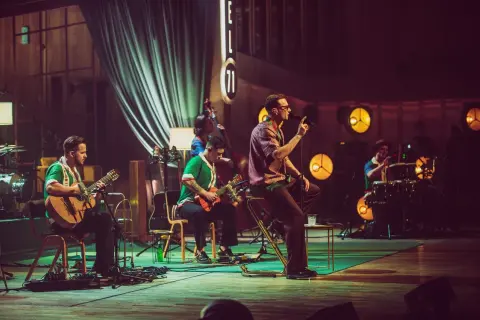 Zespół Mrozu na scenie MTV Unplugged. Wokalista śpiewa, gitarzyści grają, a perkusista wybija rytm.
