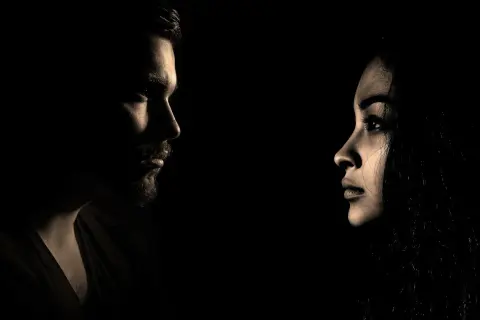 Profili di un uomo e una donna si fronteggiano nel buio, un'immagine che evoca il silenzio dopo la fine di una storia.