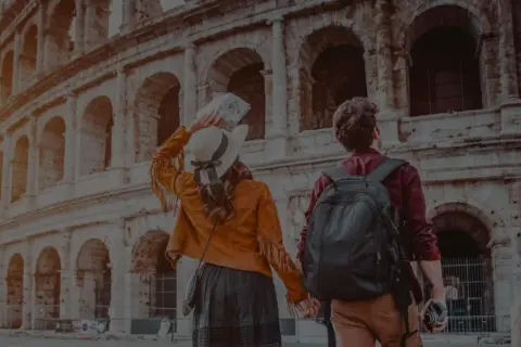 Ett par håller hand framför Colosseum i Rom. Trots att det är december är temperaturen behaglig för turister.