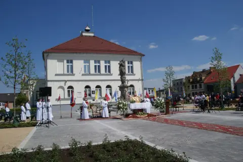Uroczystość religijna na rynku w **Borku Wielkopolskim**. Kapłan odprawia mszę, towarzyszą mu ministranci i wierni.