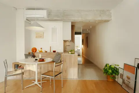 Stilvolle Einrichtung einer 45 qm Wohnung mit Esstisch, Küche und Blick ins Schlafzimmer. Helle Farben und Holzmöbel schaffen Gemütlichkeit.
