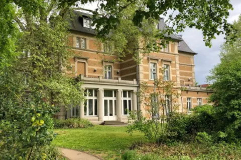 Prachtvolle Villa Zanders, umgeben von üppigem Grün, mit einem Weg, der sich durch den Garten schlängelt.