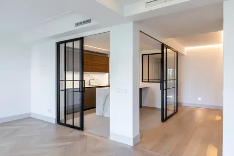 Puertas correderas de cristal negro separan la cocina moderna. Se planea poner baldas entre dos paredes para maximizar el espacio.