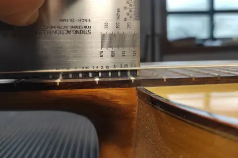 Ajustando la altura de las cuerdas de una guitarra flamenca con una regla de acción.