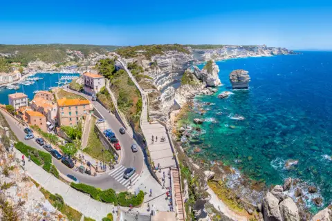 Vue panoramique de Bonifacio, Corse. La ville perchée sur les falaises blanches surplombe un port animé et une mer turquoise. Idéal pour visiter Bonifacio.