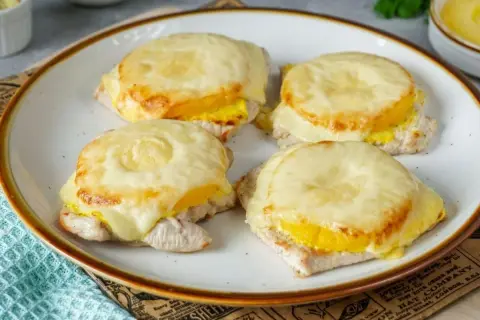 Vier saftige Schnitzel Hawaii mit geschmolzenem Käse und Ananasringen, appetitlich auf einem Teller angerichtet.