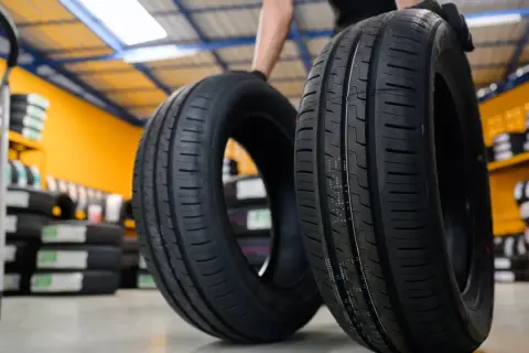 Deux pneus de voiture neufs, une sous-marque Michelin, sont présentés dans un entrepôt rempli de pneus.
