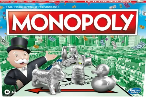 Pudełko gry Monopoly z Mr. Monopoly, pionkami i pieniędzmi na tle miasta.