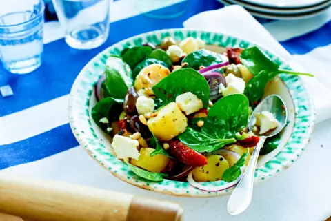 En härlig hemmagjord potatissallad med färsk spenat, fetaost, oliver och soltorkade tomater. Perfekt till sommarlunchen!