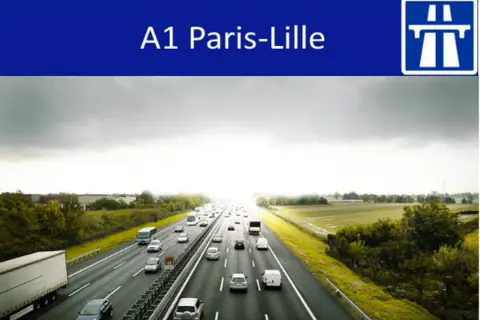 Trafic dense sur l'autoroute A1 Paris-Lille sous un ciel couvert. Des voitures et camions circulent sur plusieurs voies.