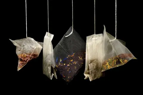 Cinq sachets de thé suspendus, révélant des mélanges variés de marc de thé et de fleurs séchées.