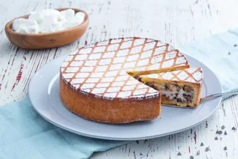 Une délicieuse cassata al forno, saupoudrée de sucre glace, avec une part coupée pour révéler sa garniture crémeuse et chocolatée.
