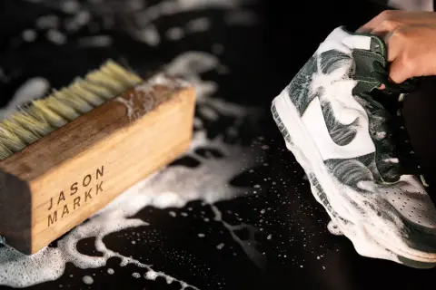 Une chaussure est savonneuse, prête à être nettoyée avec une brosse. Le processus pour **laver chaussures machine** est en cours.